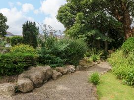 A garden with a pathway and various plants at Tyddyn Iolyn in Benllech