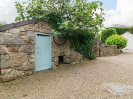 A stone building with a blue door and surrounding greenery at Tyddyn Iolyn in Benllech