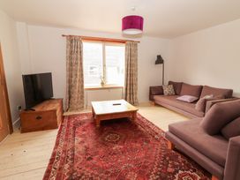 A living room with a sofa, coffee table, and television at Shanti Gher in Bantry