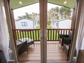 A balcony with two wicker chairs and a small table viewed through sliding glass doors at Casa Cayton Beach in Scarborough