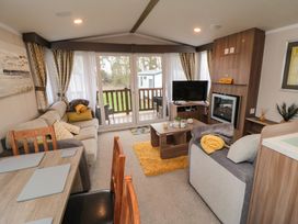 A living room with a sofa dining table sliding glass doors and a television at Casa Cayton Beach in Scarborough