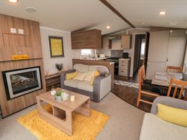 A living room with sofas and a coffee table next to a fireplace and an open kitchen with a dining table at Casa Cayton Beach in Scarborough