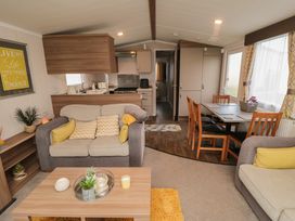 A living room with sofas and a coffee table next to a dining area with wooden chairs and table at Casa Cayton Beach in Scarborough
