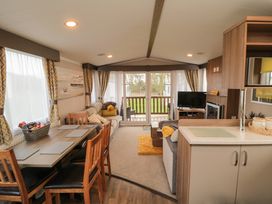 A living area with a dining table chairs sofas a television fireplace and large windows at Casa Cayton Beach in Scarborough