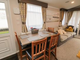 A dining table with four wooden chairs next to a window and a sofa with cushions and blankets at Casa Cayton Beach in Scarborough