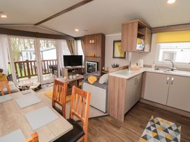 An open living room and kitchen with wooden dining table chairs sofa tv and fireplace at Casa Cayton Beach in Scarborough