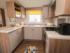 A kitchen with cabinets stove microwave and sink with a yellow window blind at Casa Cayton Beach Scarborough