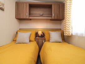 A bedroom with two single beds with yellow bedding and a small lamp on a wooden nightstand between them at Casa Cayton Beach in Scarborough