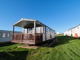 A mobile home with a covered wooden porch on grass in a residential park at Casa Cayton Beach in Scarborough