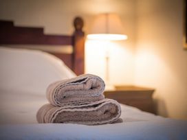 A bed with rolled towels and a lamp at The Coach House in Lydford