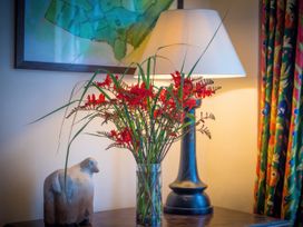 A vase with flowers and a lamp on a table at The Coach House in Lydford