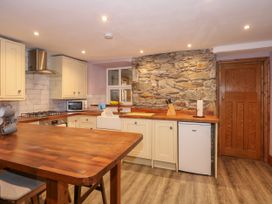 A kitchen with wooden countertops a stone wall cabinets and a wooden table at Miners Rest in Blaenau Ffestiniog