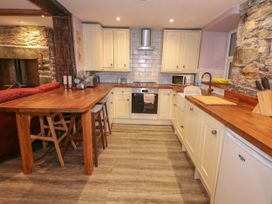 A kitchen with wooden countertops cream cabinets a stove and stools at Miners Rest in Blaenau Ffestiniog