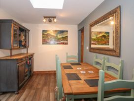 A dining room with a wooden table and green chairs a wooden cabinet and a large framed mirror at Miners Rest in Blaenau Ffestiniog