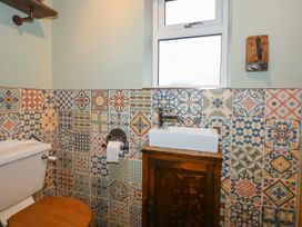 A bathroom with a toilet wooden seat patterned tiles and a small sink on a wooden cabinet at Miners Rest in Blaenau Ffestiniog