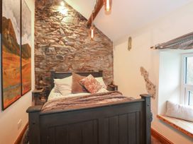 A bedroom with a stone wall behind a bed and a window seat with a cushion at Miners Rest in Blaenau Ffestiniog