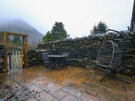 An outdoor patio with a stone wall table and chairs and a hanging chair at Miners Rest in Blaenau Ffestiniog