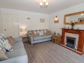 A living room with two grey sofas a wooden fireplace and a striped carpet at Pebble Cottage in Whitby