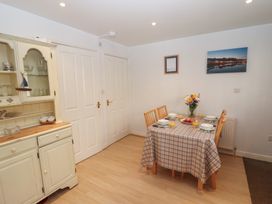A dining area with a table set for six people and a cabinet with glassware at Pebble Cottage in Whitby