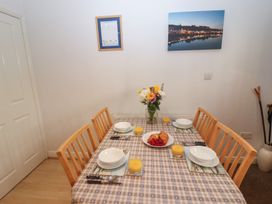 A dining room table set with bowls, glasses of orange juice, croissants, raspberries, and a vase of flowers at Pebble Cottage in Whitby