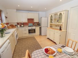 A kitchen with white cabinets a refrigerator a wooden cabinet and a table set with croissants raspberries and orange juice at Pebble Cottage in Whitby