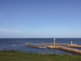 View of a pier and lighthouse over the sea at Pebble Cottage in Whitby