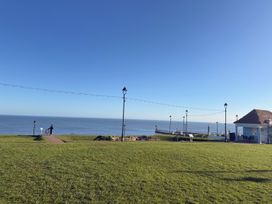 An outdoor area with grass and a path leading to the ocean at Pebble Cottage in Whitby