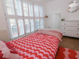 A bedroom with a bed, dresser, mirror, and shuttered windows at Betty's Buoy in Weymouth