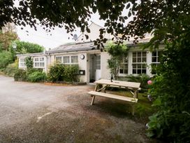 A house exterior with a bench and bushes at Pippins in Ambleside