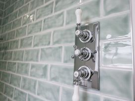 A shower control panel on green tiled wall at Pippins Ambleside