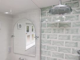 A bathroom with shower head and mirror at Pippins in Ambleside