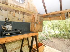 A small outdoor wooden kitchen setup with a stove kettle and hanging utensils at Brandon House Farm Yurt Brandon Parva near Mattishall
