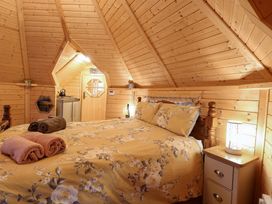 A bedroom with a floral bedspread and rolled towels on the bed in a wooden cabin at Enchanted Cottage in Snettisham