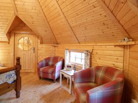 A wooden room with two plaid armchairs a small white table and a window at Enchanted Cottage in Snettisham