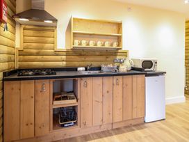 A kitchen with wooden cabinets a stove a microwave a mini fridge and a kettle at Rabbit Warren Lodge in Snettisham
