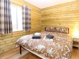 A bedroom with a double bed brown animal print duvet and folded towels on it next to a window with plaid curtains at Rabbit Warren Lodge in Snettisham