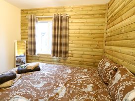 A bedroom with a bed covered in animal print bedding a window with plaid curtains and a standing mirror at Rabbit Warren Lodge in Snettisham