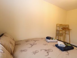 A bedroom with a bed with animal print bedding and a wooden clothes rack with hangers at Rabbit Warren Lodge in Snettisham
