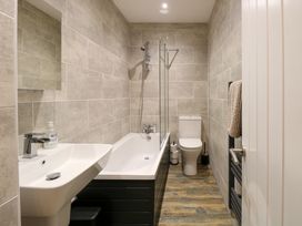 A bathroom with a bathtub shower combination sink toilet and towel rack at Rabbit Warren Lodge in Snettisham