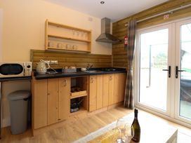 A kitchen area with wooden cabinets microwave kettle sink and sliding glass doors at Robins Nest Lodge in Snettisham
