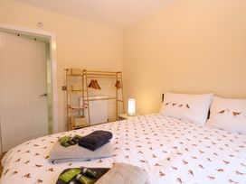 A bedroom with a bed with bird patterned bedding a wooden clothes rack with hangers and woven baskets at Robins Nest Lodge in Snettisham