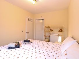A bedroom with a bed with bird patterned bedding towels on the bed a clothes rack with hangers and baskets and two white doors at Robins Nest Lodge in Snettisham