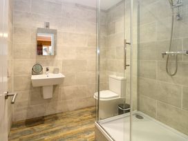 A bathroom with a shower enclosure a toilet a wall-mounted sink and a mirror at Robins Nest Lodge in Snettisham