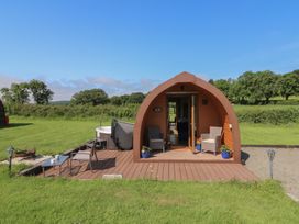 A glamping pod with a wooden deck and outdoor seating at Ty Twt Teifi in Tregaron