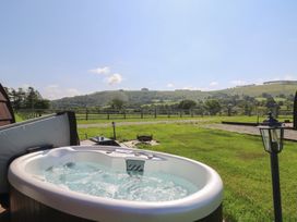 A hot tub on grass with a view of hills at Ty Twt Teifi in Tregaron