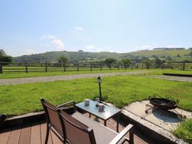 An outdoor seating area with a table and chairs and a view of the mountains at Ty Twt Teifi in Tregaron
