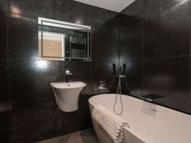 A bathroom with a bathtub, sink and mirror at Number 7 in Bishop Sutton