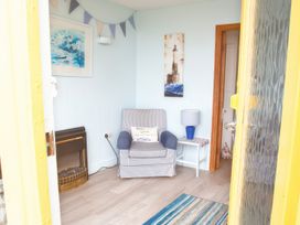 A small sitting area with an armchair a side table with a lamp a fireplace and wall art at Homestead Aberdesach near Penygroes