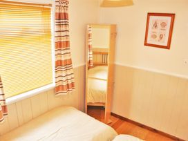 A bedroom with two beds a standing mirror window with blinds and curtains and a framed shell picture on the wall at Homestead Aberdesach near Penygroes