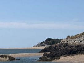 A beach with rocks and a house in the background at The Quarterdeck in Borth-Y-Gest